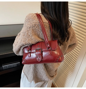 Detail of red glossy leather shoulder bag with vintage belt buckle and silver rivets