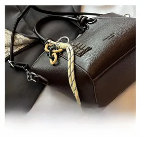 Detail of dark brown pebble leather bag with woven charm and detachable strap