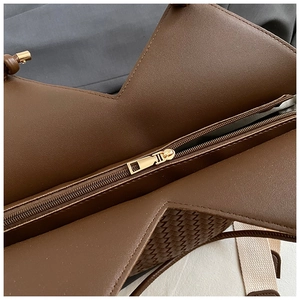 Close-up of golden metal zipper and woven leather texture on dark brown tote bag