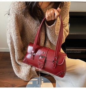 Detail of dark red faux leather underarm bag with silver rivets and buckle decoration