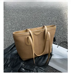 Detailed outdoor shot of brown canvas tote bag with leather straps on a black jacket