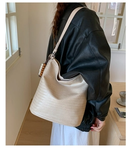 Detail of beige woven hobo bag with decorative wooden beads and ivory charms