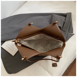 Top view of spacious interior of brown leather tote bag with zipper pocket and knotted detail