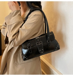 Detail of glossy black vintage shoulder bag with wide belt buckle and metal rivets