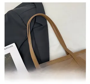 Detail of khaki canvas tote bag with brown leather handles and stitching