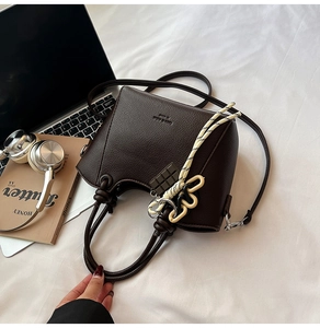 Detailed view of dark brown pebbled leather handbag with woven rope and chocolate charm