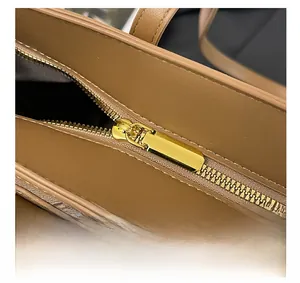 Detail of smooth gold metal zipper and stitching on brown vintage tote bag