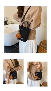 Détail d'un sac seau noir chic avec charm ours en peluche marron et bandoulière réglable