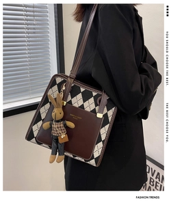 Detail of checkered woven shoulder bag with brown leather pocket and rabbit doll charm