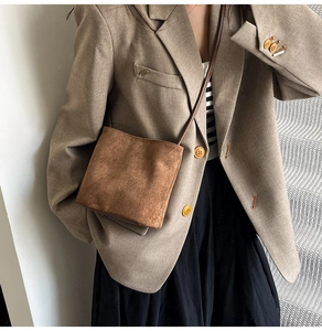 Détail du sac seau en daim marron vintage porté avec un blazer café élégant