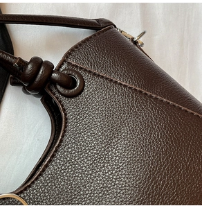 Detailed view of dark brown lychee grain leather texture with silver hardware and drawstrings