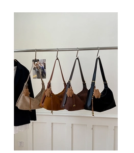 Detail of four matte suede hobo bags in neutral tones with star charms on hangers