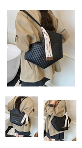 Detail of black woven leather tote bag featuring a V-shaped cut and printed ribbon