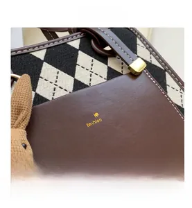 Detail of argyle knit fabric and brown leather with gold logo on a vintage handbag