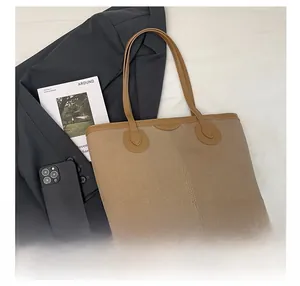 Detail of khaki canvas tote bag with brown leather handles and spacious reinforced base