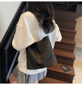 Dettaglio della trama e della tracolla in pelle della borsa a spalla nera minimalista