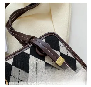 Close-up of argyle fabric texture and premium leather stitching on a stylish shoulder bag