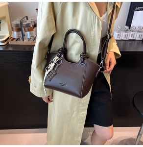 Detail of dark brown leather bucket bag with knotted handle and chocolate charm pendant
