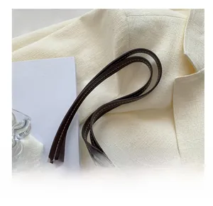 Close-up of dark brown leather handbag strap featuring distinct white contrast stitching