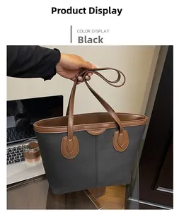 Close-up of black canvas tote bag with brown leather handles in a professional work setting