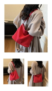 Dettaglio della borsa a secchiello rossa intrecciata con texture e tracolla larga