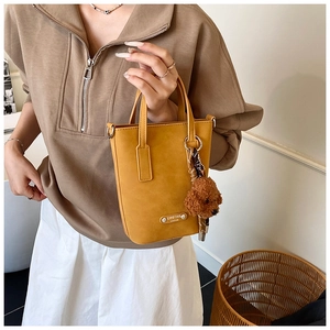 Détail d'un sac seau jaune moutarde avec charm ourson et finitions en métal argenté