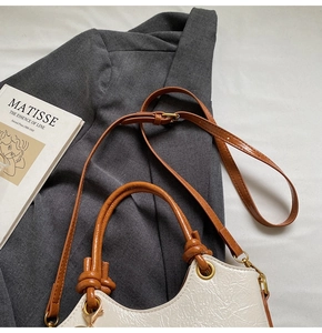 Detail of cream pleated bucket bag with brown leather knotted handles and gold hardware