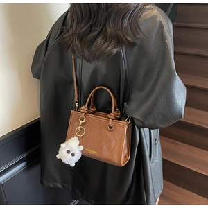 Petit sac seau en cuir marron avec breloque peluche et lettrage doré élégant