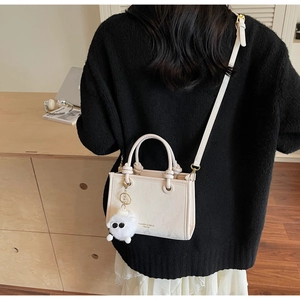 Détail du sac seau bandoulière en cuir crème avec breloque peluche et sangle