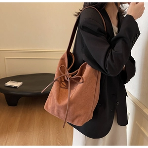 Brown suede tote bag with drawstring bow detail shown on a model for daily commute