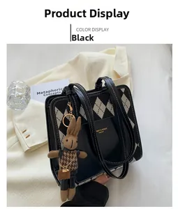 Detail shot of black and white lattice tote with golden logo and cute bunny charm
