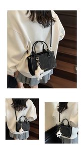 Détail du sac seau noir avec inscription dorée et accessoire de charme poupée en peluche blanche