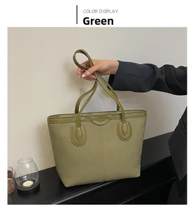 Detail of green matte tote bag featuring vertical stitching and leather handles