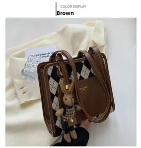 Detailed view of the brown leather and knit diamond pattern bag with rabbit pendant