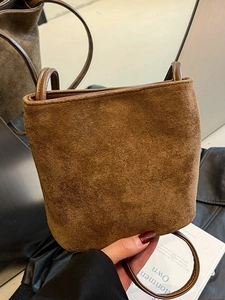 Sac seau vintage en daim marron avec bandoulière longue dans un miroir au style minimaliste