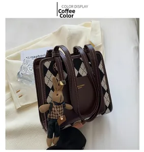 Detail of coffee brown quilted handbag with gold logo and plush rabbit charm on blazer