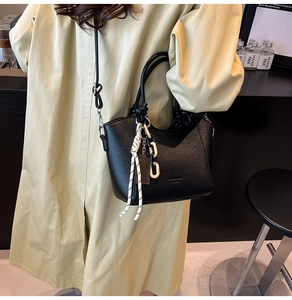 Black pebbled leather bucket bag with white rope detail and acrylic chain strap