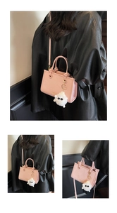 Détail d'un sac à main en cuir rose avec breloque peluche blanche et bandoulière longue