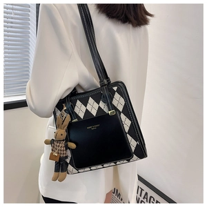 Detail of checkered canvas shoulder bag with plush bunny charm and brand logo