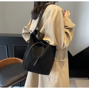 Detail of black nylon drawstring bucket bag with bow tie shown on model's shoulder
