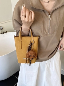 Sac seau chic en daim jaune moutarde avec charm ourson dans un cadre moderne