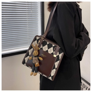 Detail of crossbody bag featuring argyle pattern, brown pocket, and cute rabbit charm