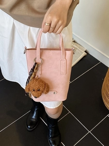 Sac seau rose minimaliste avec breloque chien en peluche et sangle tissée en vue de dessus