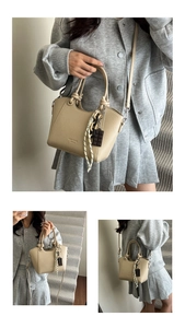 Detail of khaki leather bucket bag with litchi texture and stylish knot handle design