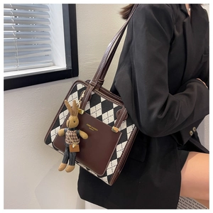 Detail of vintage plaid shoulder bag featuring black and white lattice fabric and rabbit charm