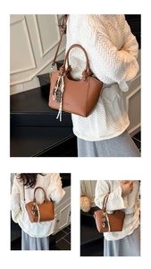 Close-up of brown faux leather handbag featuring a curved handle and striped ribbon charm