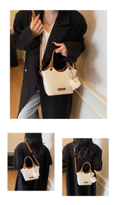 Detail of a beige bucket bag with brown handles and a cute white sheep charm accessory