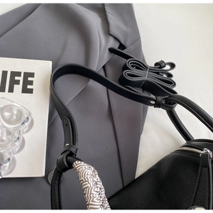 Detail of black lychee grain pillow bag with geometric silk scarf handle and silver zipper