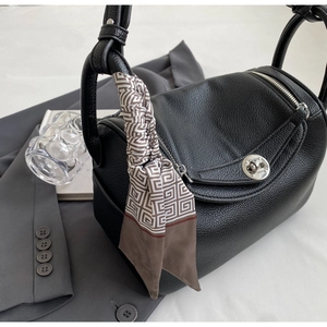 Detail of black lychee grain leather bag with metal twist lock and geometric silk scarf decoration