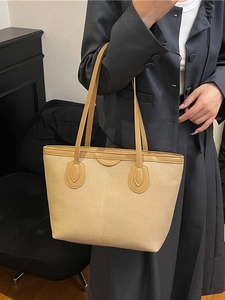 Minimalist matte beige tote bag with faux leather trim worn by model in gray suit